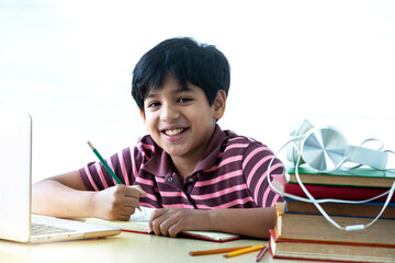 Indian school boy are happy while studying online lesson at home, looking and smile with camera