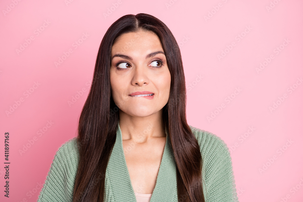Photo of worried young lady bite lip look empty space wear green cardigan isolated pastel pink color background - obrazy, fototapety, plakaty 