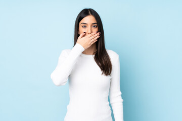 Young caucasian woman isolated on blue background covering mouth with hand