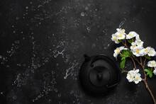 Asian Metal Teapot And Blossom Cherry Branch (artificial) On A Black Stone Background. Black Cast Iron Teapot. Top View.