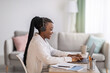 © Prostock-studio - Positive black woman with headphones sitting in front of laptop