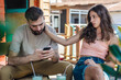 © guruXOX - Alienation addiction. Young couple sitting in cafe and typing on their own phones