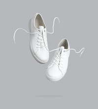 Flying White Leather Womens Sneakers Isolated On Gray Background. Fashionable Stylish Sports Casual Shoes. Creative Minimalistic Layout With Footwear Mock Up For Your Design Advertising For Shoe Store