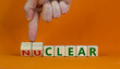Nuclear or clear symbol. Businessman turns a cube and changes the word 'nuclear' to 'clear'. Beautiful orange background. Nuclear or clear and business concept. Copy space.