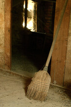 Vertical Shot Of An Old Broom Leaned On The Wall Of A Barn
