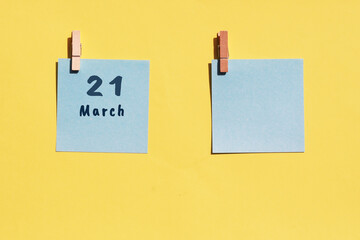 March 21st. Day of 21 month, calendar date. Two blue sheets for writing on a yellow background. Top view, copy space. Spring month, day of the year concept