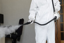 Disinfector In A Protective Suit Conducts Disinfection In Home. Professional Disinfection Against COVID-19, Coronavirus. In Clothing Protecting From Chemical Poisoning In The Industry.