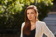 © Dmitry Tsvetkov - Young woman in black shirt, jeans and white blazer walking and posing outdoors on a summer day. Sun backlight. Outdoor portrait