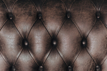 Dark brown leather sofa upholstery texture. The background surface is made of shiny luxury material close up. Copy space.