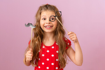 Wall Mural - A girl with curly hair holds a fancy mustache and glasses on a stick.