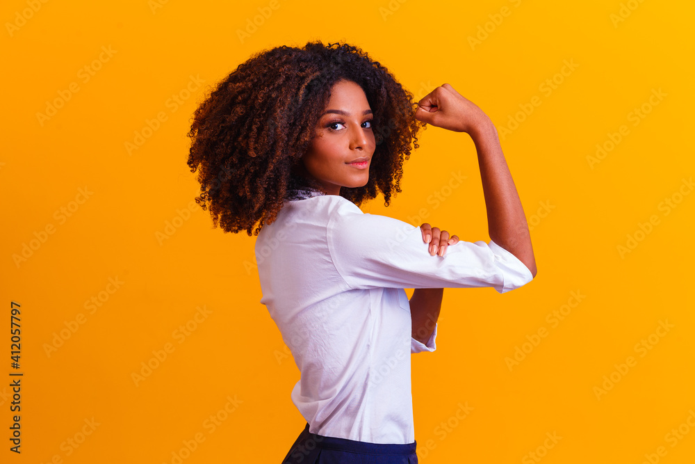 We can do it. Woman's fist of female power. Woman victim of racism. Abuse at work. The feminine power. Female empowerment. The strength of women. Yellow background. - obrazy, fototapety, plakaty 