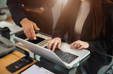 Business, technology and office concept - two businessmen with laptop, tablet pc computer and papers having discussion in modern office.