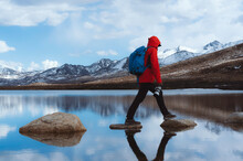 Man Walking On Stepping Stones In Lake Against Snowcapped Mountain