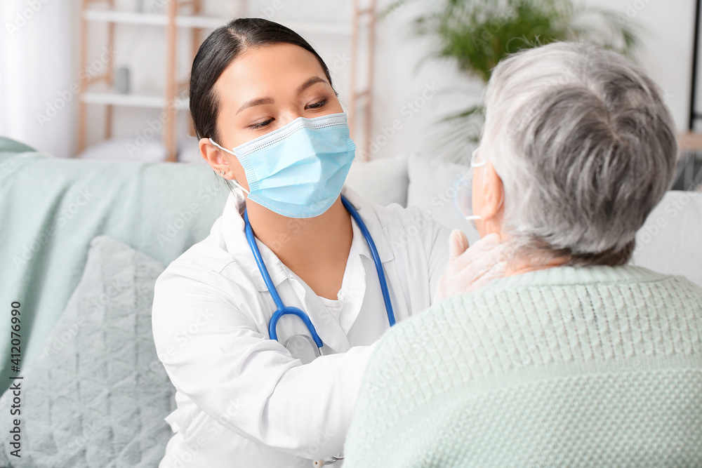 Doctor examining senior woman at home