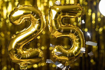 Golden number 25 twenty five made from an inflatable balloon, on a yellow background. One of the complete set of numbers. The concept of birthday, anniversary, date