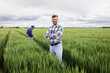 © Zoran Zeremski - Portrait of farmer standing in green wheat field with his colleague in background.