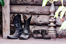 Selective Focus Shot Of A Pair Of Old Shoes And Cowboy Boots On A Porch