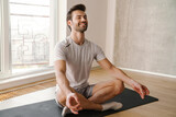 Fototapeta  - Happy athletic handsome man meditating after workout at home