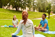 © Syda Productions - fitness, sport and healthy lifestyle concept - group of happy people sitting on yoga mats at park and talking