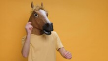 Funny Dance Young Man In Horse Mask Rhythmically Moving His Arms Up Down On Music On Yellow Background. Crazy Fun Dancing Hipster. Happiness Holidays. Face Horse. Positive Emotion. Humor