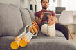 © Studio Romantic - Young man with broken leg in plaster cast sitting on sofa and using tablet computer. Close up of foot and crutches. Physical injury, bone fracture, treatment and rehabilitation at home concept