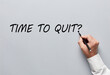 © Cagkan - Businessman hand writing the question of time to quit on gray background. Deciding to quit job or to exit business