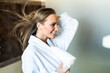© F8  \ Suport Ukraine - Beautiful young dries her hair with a hairdryer while looking in her reflection in a large mirror. The concept of personal care and shampooing. Harm from drying with a hair dryer