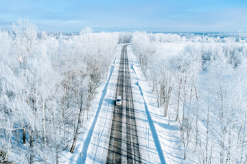 Wall Mural - Aerial view of winter road with a car and snow covered trees.