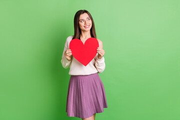 Wall Mural - Photo of young lovely beautiful happy positive cheerful girl hold big red heart look copyspace isolated on green color background