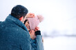 © Viorel - Rear photo of loving man pulling down his laughing girlfriend pink hat, having fun together outside, enjoying winter day, snowy weather. Cute couple playing in the park. Side empty space