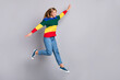 © deagreez - Full length body size photo of funny playful girl jumping high plane wings colorful sweater isolated on pastel grey color background