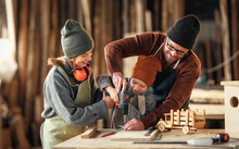 Happy Family Doing Woodwork Together In Workshop