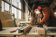© JenkoAtaman - Woodworker cutting wood in workshop