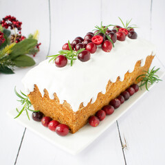 English cake on a white plate with cranberries and rosemary. Christmas cake.