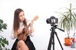 © Enrique Micaelo  - Young woman with guitar creating online content on white background with copy space