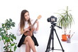© Enrique Micaelo  - Young woman with guitar creating online content on white background with copy space