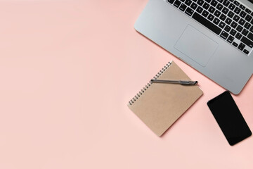 Office stuff, laptop, notebook, pen and smartphone on pink pastel color background for business and education concept. Top view with copy space.