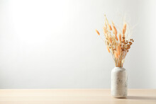 Dried Flowers In Vase On Table Against Light Background. Space For Text