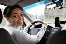 Rear View Of Attractive Young Woman In Casual Wear Looking Over Her Shoulder While Driving Car