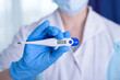 © Денис Прокофьев - Hand in blue glove holding a digital thermometer on white background. Medical worker wearing protective gloves checking medical thermometer.