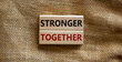 Stronger together symbol. Concept words 'stronger together' on wooden blocks on a beautiful canvas background. Business, motivational and stronger together concept.