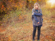 A woman of 40 years in autumn nature landscape. The blonde woman wears clothes made of wool and boots.
