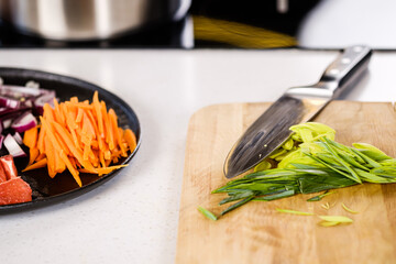 Wall Mural - The cook cuts vegetables, peppers, onions and carrots on a chopping board