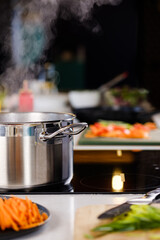 Wall Mural - Cooking in the kitchen. Sliced vegetables on a plate. Boiling water in a saucepan on an induction stove.