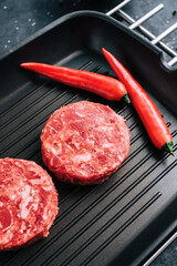 Wall Mural - Fresh raw minced beef steak for burgers on black grill pan with chili pepper.