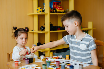 A boy and a girl play together and paint. Recreation and entertainment. Stay at home