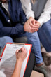 © Roman - female psychologist listening to couple and making notes in document on clipboard, close-up. focus on paper and hand
