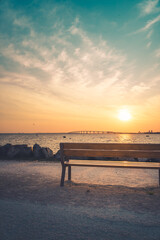 Isolated public bench at sunrise. Re island bridge in the background. portrait format