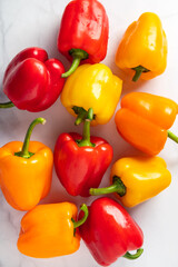 Fresh vegetables, colorful orange, red and yellow bell peppers on marble background