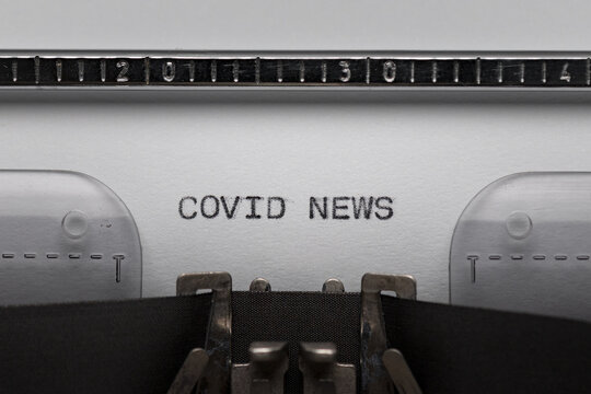 Typing text COVID NEWS on vintage manual typewriter. Close up of writes word on white paper. Shot in macro. Concept of Coronavirus.